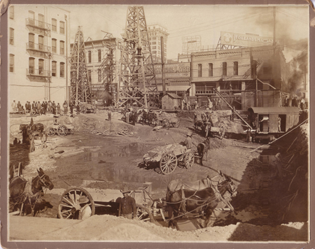 Picutre of Vilbig Brother's Construction performed the excavation of the basement of the Adolphus Hotel at Akarad & Commerce. A steam shovel, far right, dug excavated material and wagons with mules removed the material from the site. Picture is dated 1911.